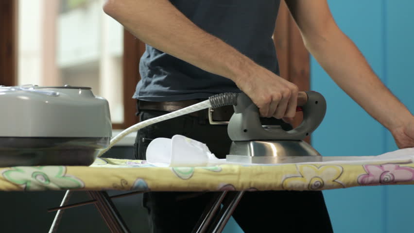 panning on caucasian adult man ironing white shirt at home