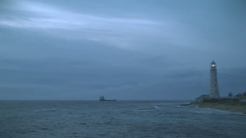 Blinking lighthouse in the evening, ship on a horizon, cloudy blue sky background. Ukraine, Crimae, Tarhankoot cape. Sound, HD