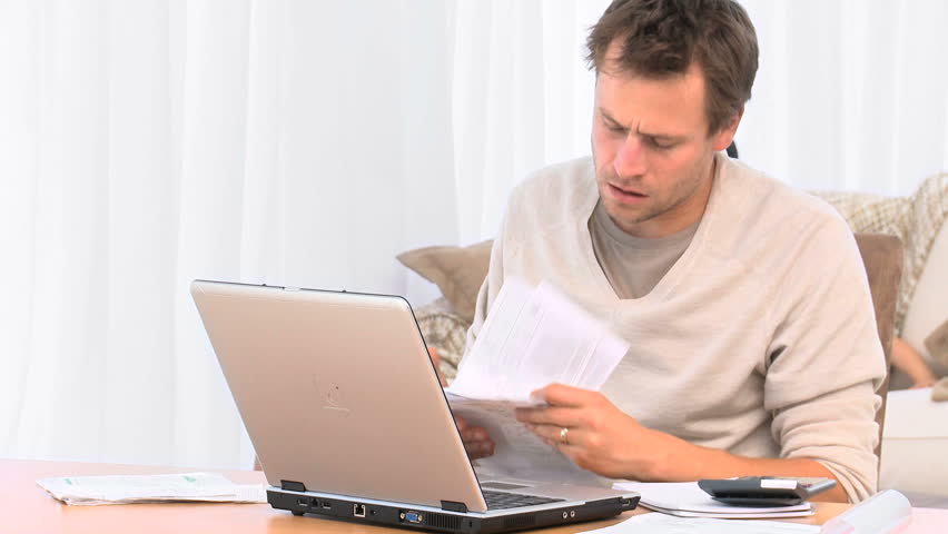 Annoyed guy calculating bills on the laptop