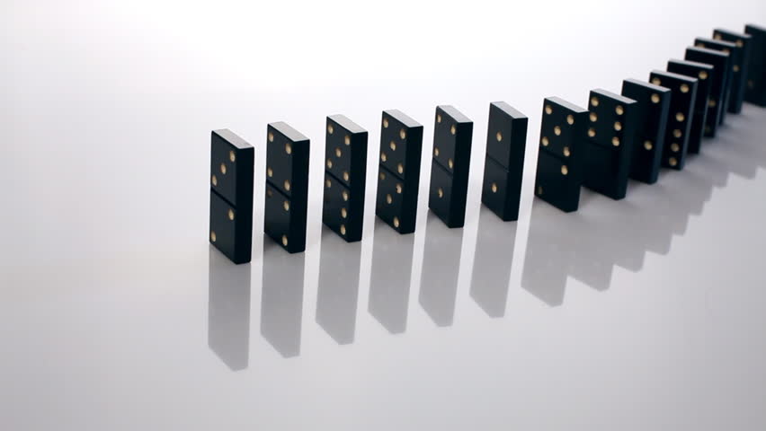 Finger pushing dominoes in a row causing a chain reaction