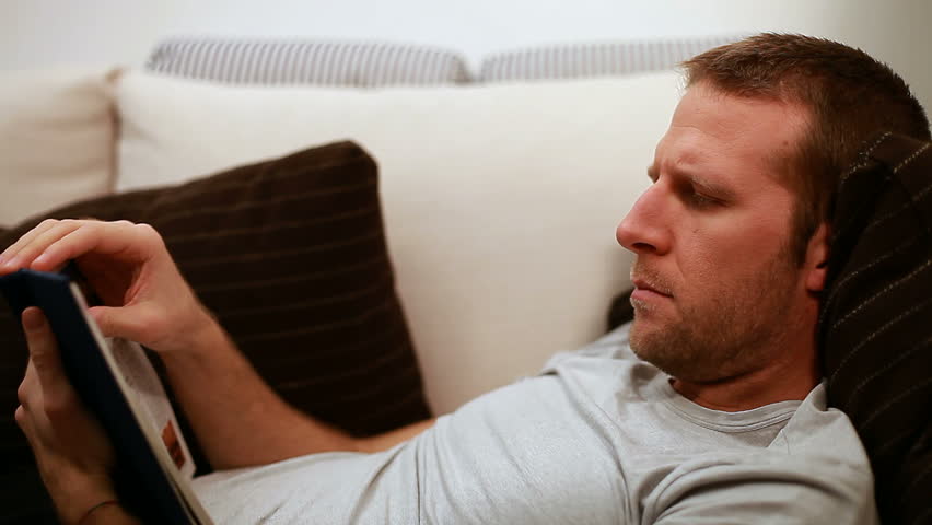 Man reading on sofa. A moment of relaxation after work.