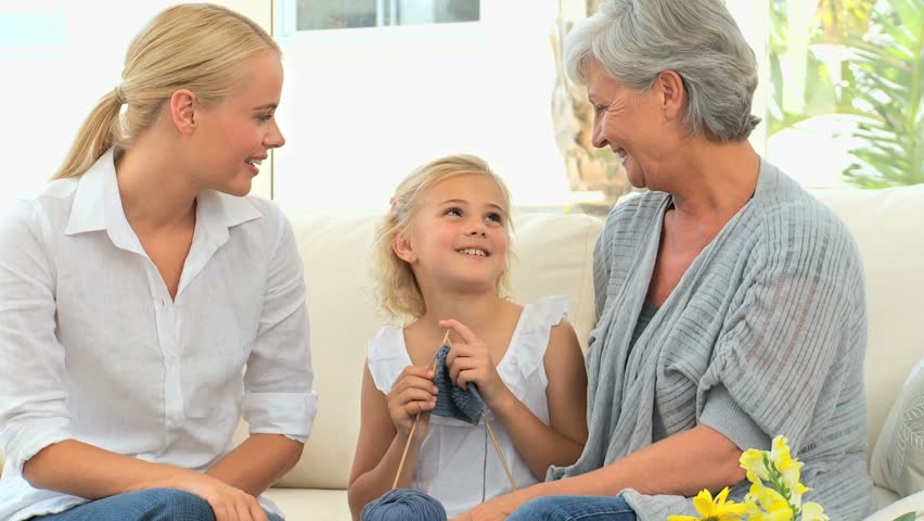 Girl knitting with her mother and Grandmother in the living room