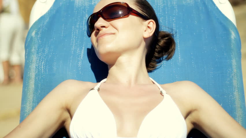 Beautiful sexy woman in white bikini taking sunbath on blue sunbed
