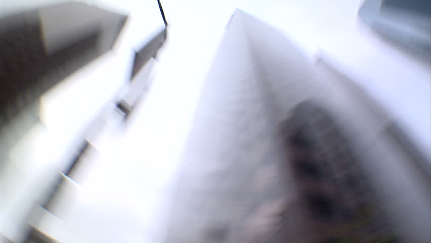 This is a looping shot looking directly up at towering skyscrapers spinning.  This shot illustrates the high energy of a bustling urban center. It can also illustrate the feeling of vertigo.