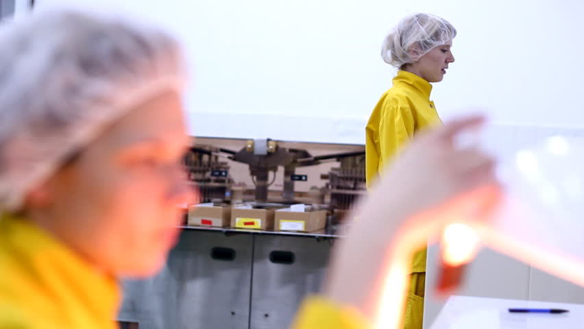 Technician inspecting the quality of glass ampules at a pharmaceutical plant.  HD 1080p.