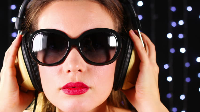 close-up of the face of a beautiful woman wearing sunglasses and headphones, listening to music