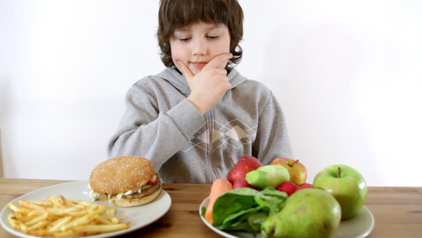 Young boy choosing vegetables and fruits instead of fast food