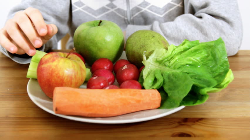 Kids hands taking healthy food, vegetables and fruits from the plate
