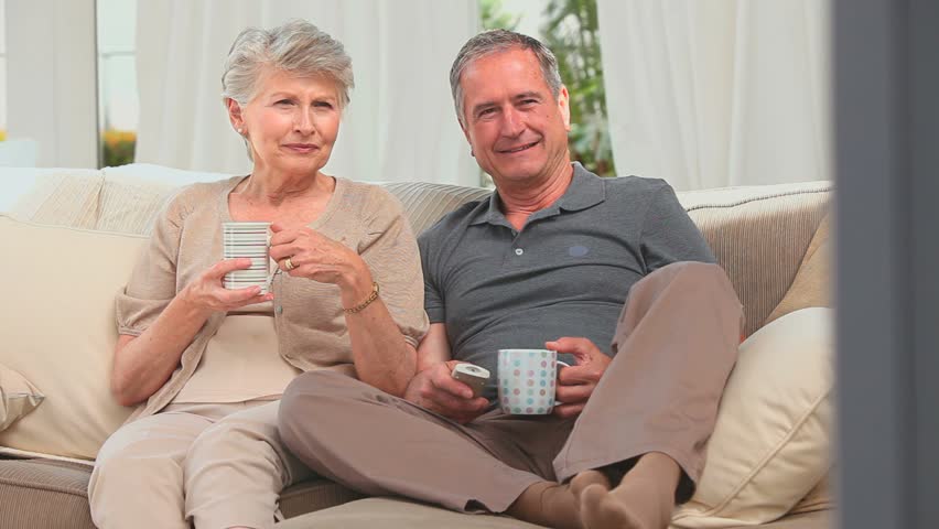 Lovely mature couple watching the tv in the living room