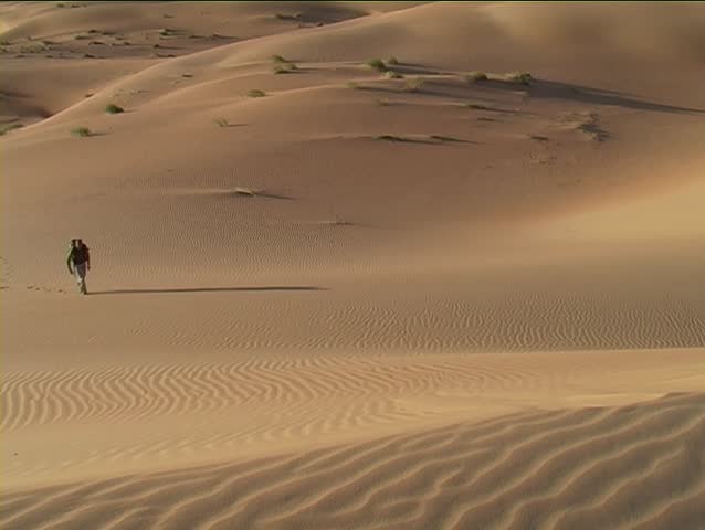 Man climbing a sand dune in the Mauritanian Sahara.