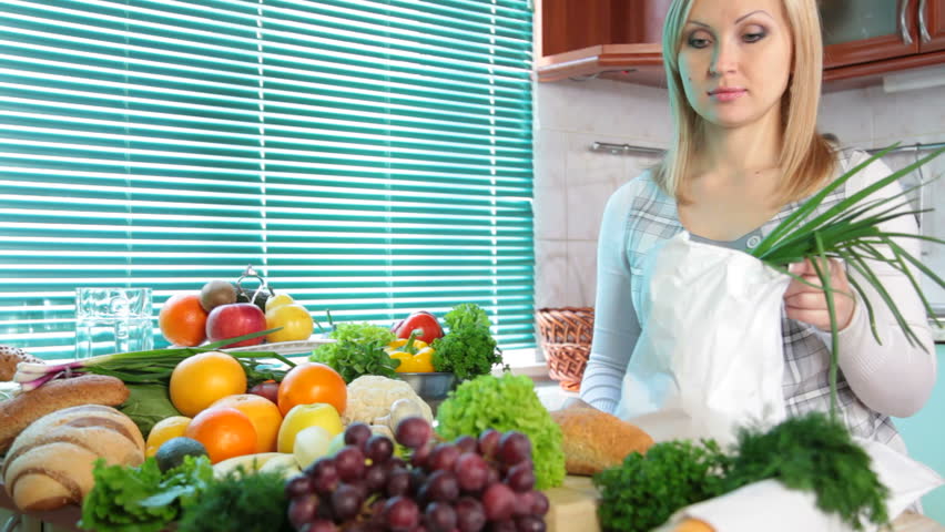 Pregnant woman Unloading Groceries from the Bag in the kitchen