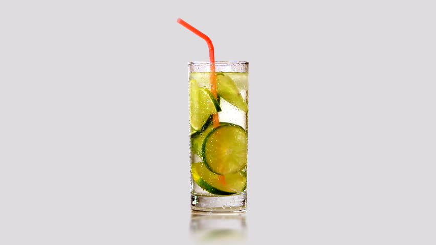 Rotating glass of lemonade with lime green. Isolated.