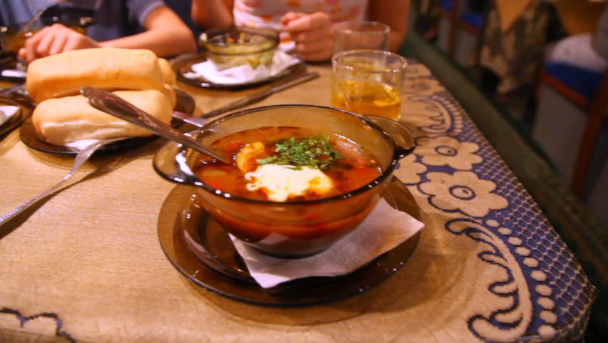 On table of dining-car is bowl with tasty hot borsch.