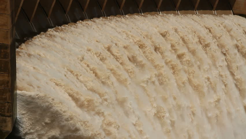 Strong flowing water with water spray and rainbow as water is released from the open sluice gates of a large dam