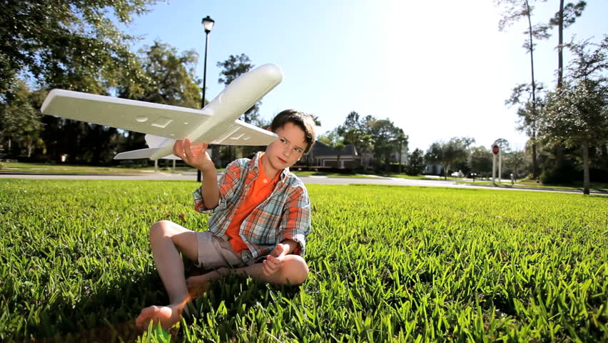 Little caucasian boy outdoors playing with toy airplane