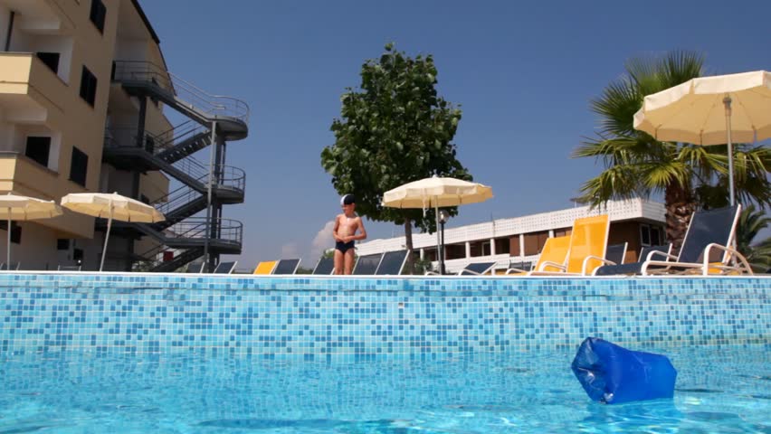 Boy in a swimming cap, took a run and closed nose jumped into the pool 