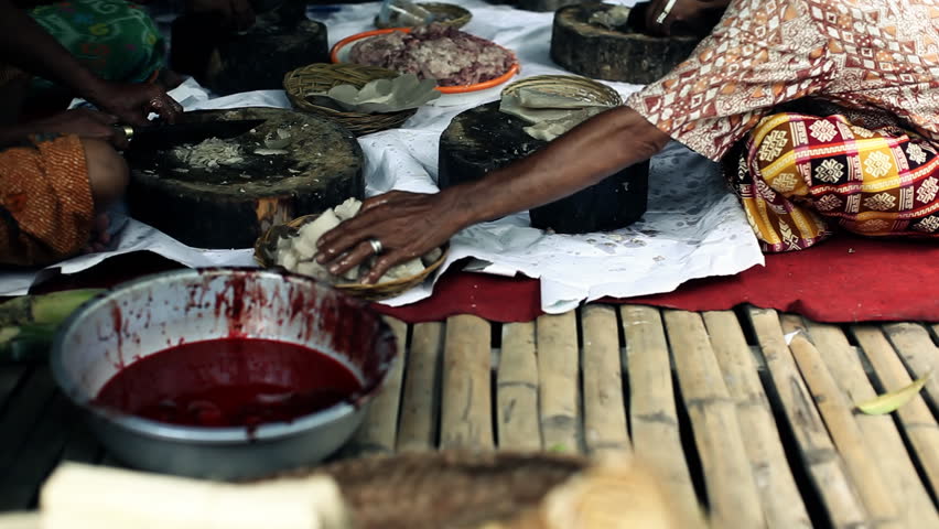 Group of indigenous balinese people sitting in a group and preparing meat for a big traditional celebration, atmospheric shot with selective focus