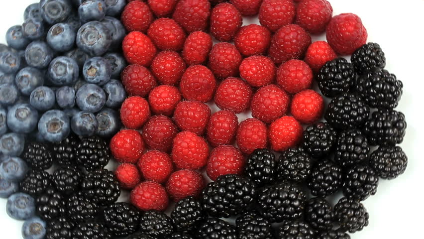 Beautiful arrangement of colorful raspberries, blueberries and blackberries rotate against white background. 1080p