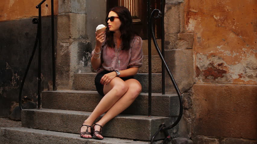 Young woman in old town eating ice cream
