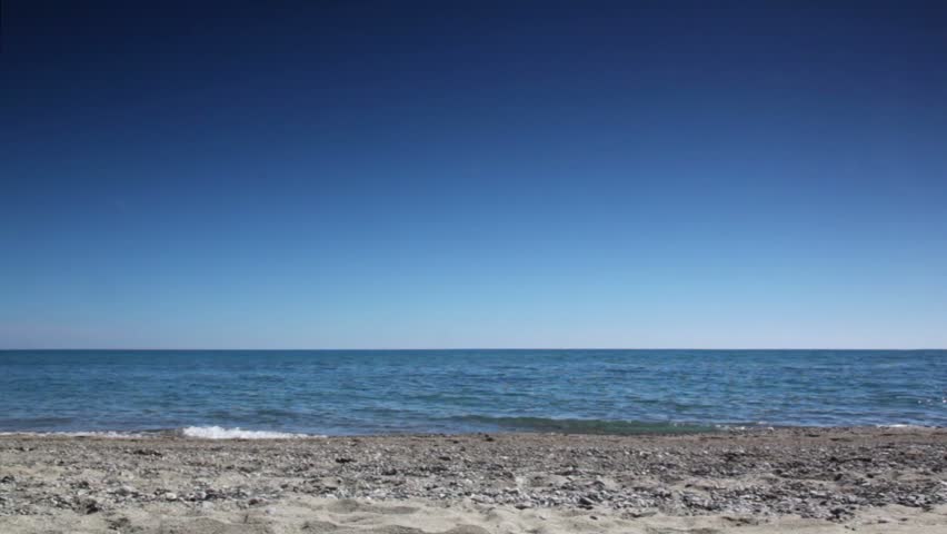 Man in brown suit walk to sea, then stand and rises hands, at summer sunny day