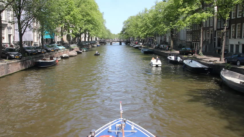 AMSTERDAM, HOLLAND - JUNE 2: Tour boat sails in Amsterdam canal, viewed overhead from a bridge on June 2, 2011 in Amsterdam, Holland. The canal ring area is on the UNESCO World Heritage List. 