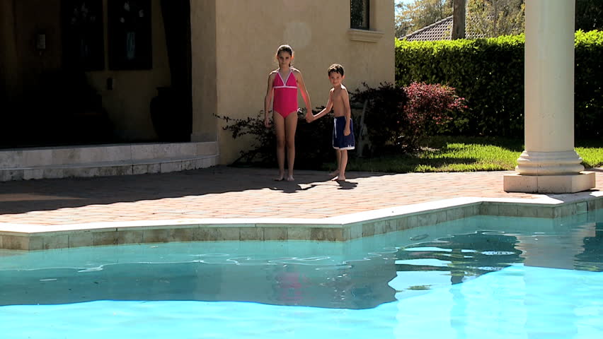 Caucasian siblings jumping into the family swimming pool