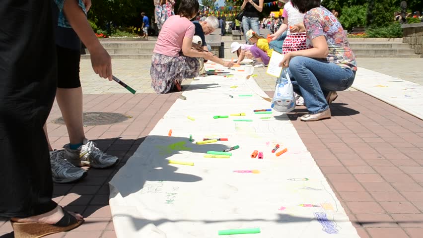 DONETSK, UKRAINE - MAY 29: Adults and children draw on a long sheet of paper in celebration of Children's Day, May 29, 2011, Donetsk, Ukraine.  First proclaimed by the United Nations General Assembly in 1954, Children's Day is observed around the world. 