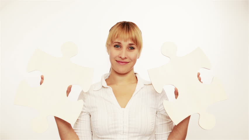 Happy young woman dancing with two oversized jigsaw pieces 