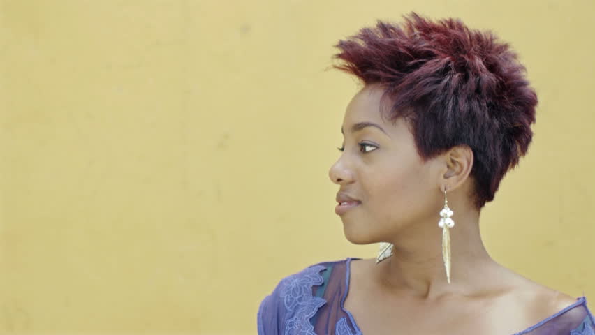 portrait of black college student smiling at camera with yellow wall in background