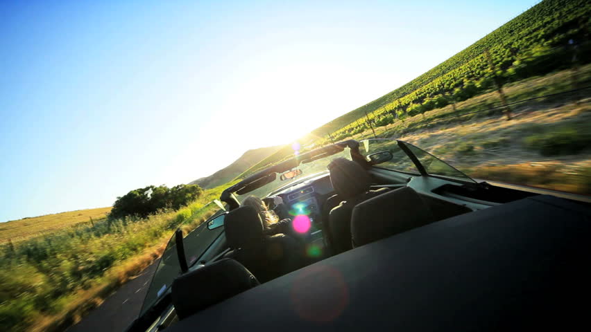 Visitors driving an open top car through the wine region of Napa Valley as the sun sets