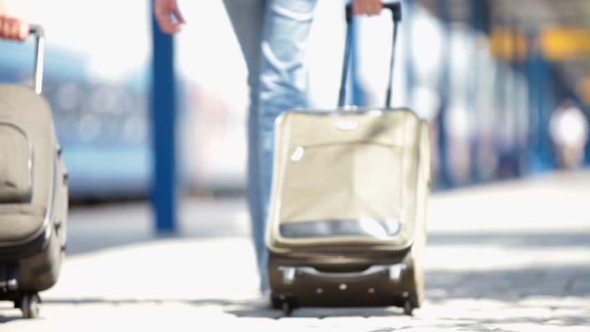 anonymous people with suitcases walk along the station platform