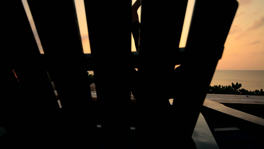 Slim athletic girl in silhouette practicing yoga overlooking the beach at sunrise