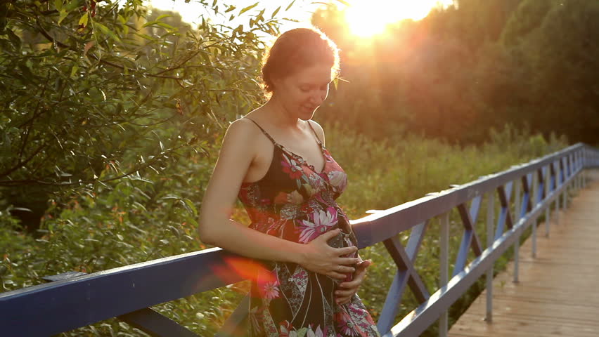 Happy pregnant woman caressing belly 