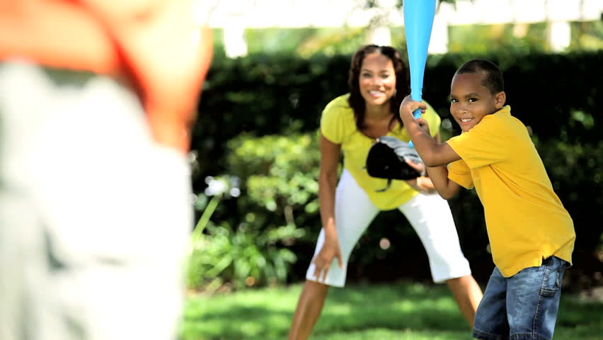 Healthy young ethnic family having fun playing baseball together in the park