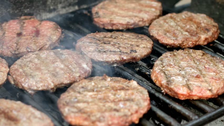 Flipping burgers on a charcoal grill.