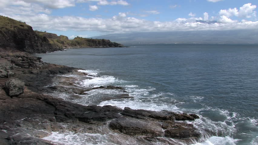 Rocky desolate shoreline on the island of Maui in Hawaii.  Beautiful water with cliffs  overlooking water. Waves splashing on rocks, scenic, relaxing and calm. 