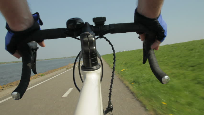 View on a steering wheel of a racing bike riding on a bicycle path in the country.