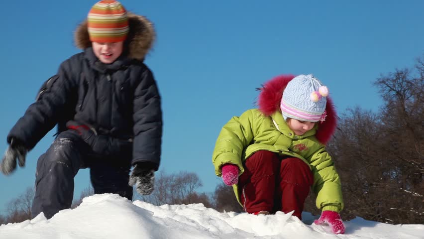 Two kids boy and girl enjoy play snowballs, girl throw snow to boys face and he become displeased, boy throw snow crust to girl and she laugh