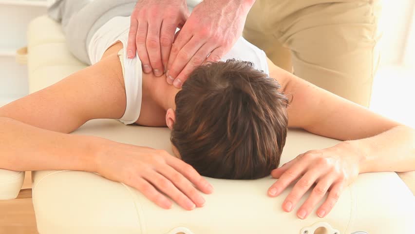 Masseur massaging a gorgeous woman's neck in a room
