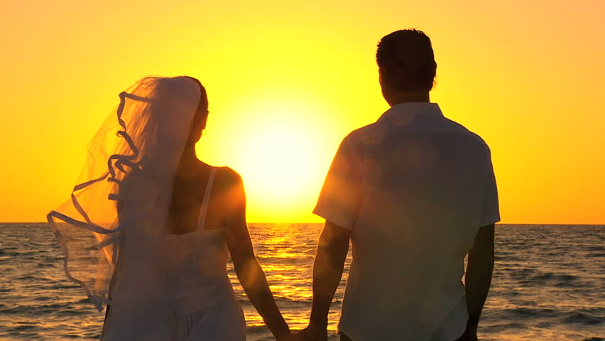 Bride & groom in silhouette at sunset on the beach after their wedding filmed at 60FPS