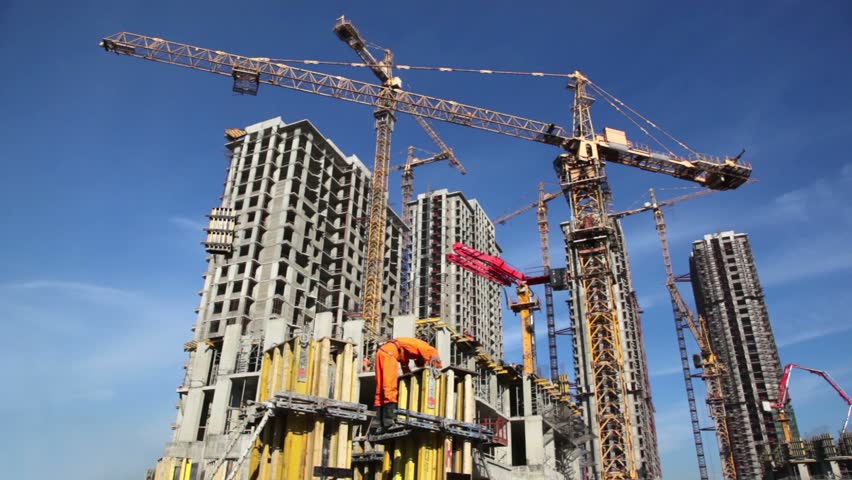 Builder works at against background of the construction site high-rise buildings 