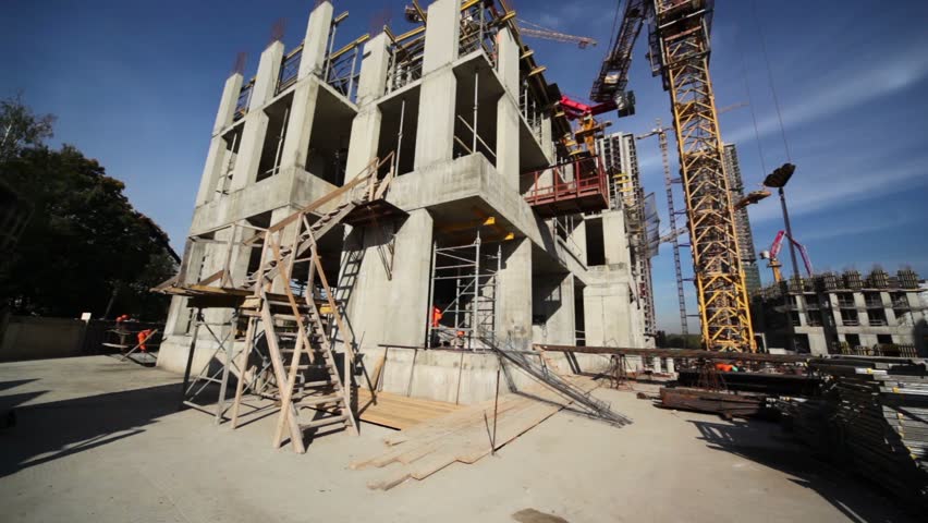 Few builders work around small unfinished edifice, tall crane stand near