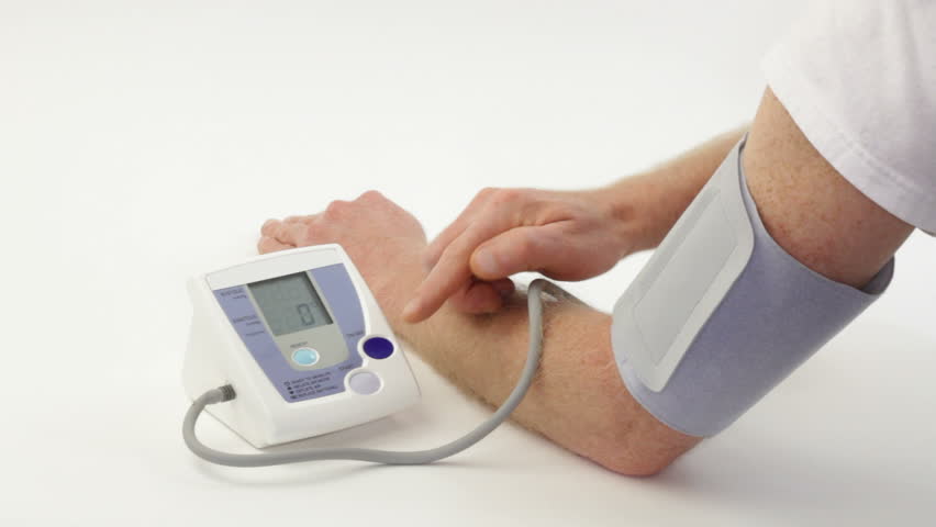 Man seen measuring his own blood pressure on a digital blood pressure monitor.