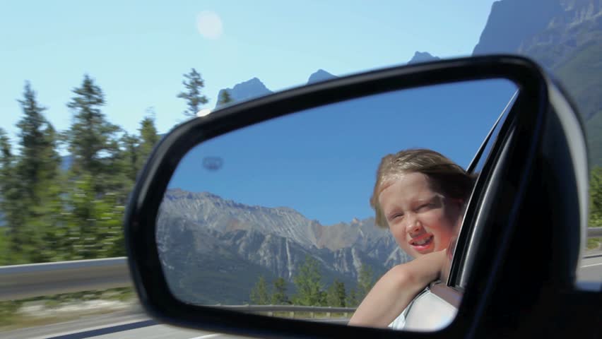 Girls reflection in a rearview mirror, moving car.