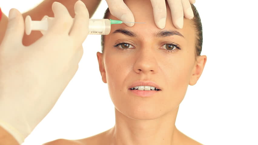 Attractive woman gets injection in her face, isolated on white