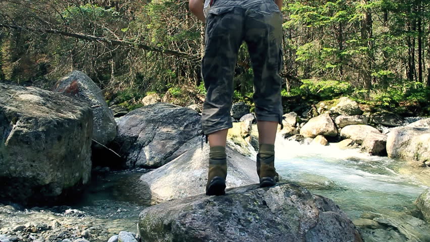 Woman running, jumping on the rocks in the forest stream, slow motion