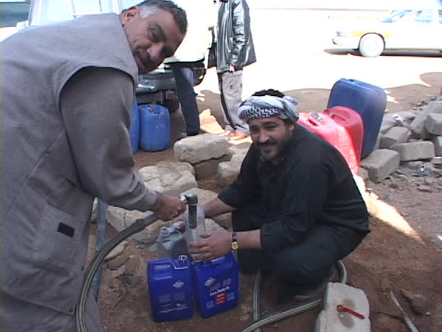 IRAQ - CIRCA 2003: Iraqi citizens siphon gas during the war's fuel shortage.