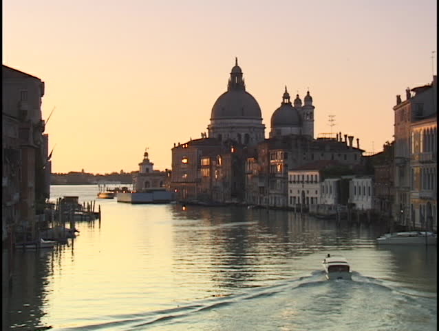 A small boat motors through the Grand Canal, passing in front of the Santa Maria del Salute in Venice, Italy.