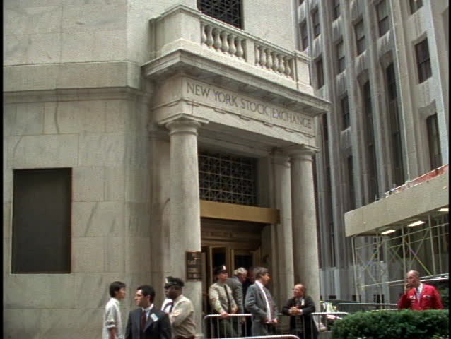 NEW YORK - CIRCA 1990's: Pedestrians walk in and out of the entrance of the New York Stock Exchange circa 1990's in New York.