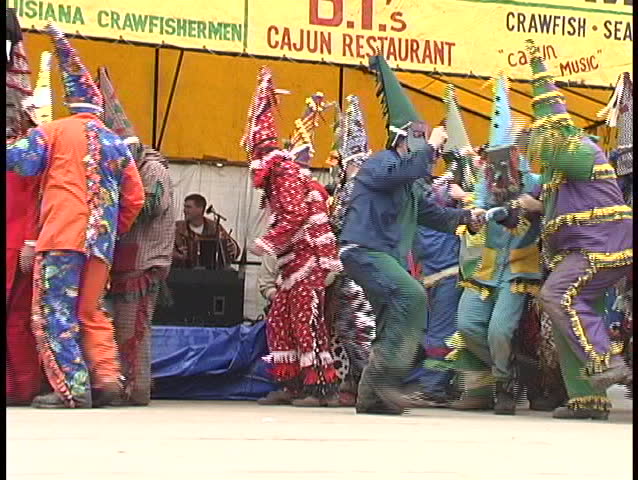 NEW ORLEANS, LA - CIRCA 2006: Mardi Gras costumed folks dance outside a tent advertising Mardi Gras sponsors or participants circa 2006 in New Orleans, LA.